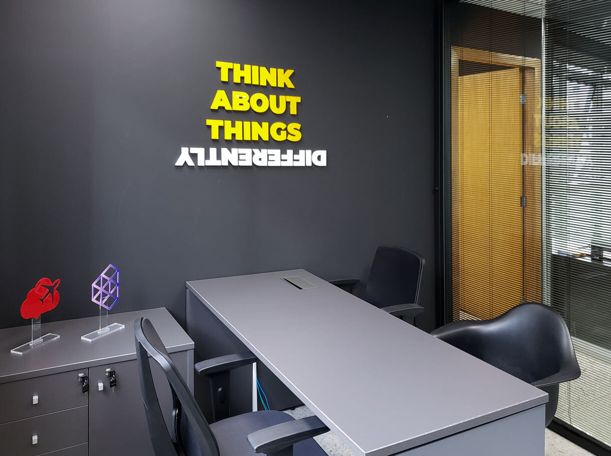 Estação de trabalho da Cubo333 com a frase Think About Things Differently na parede